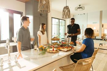 a group of people gathered around a kitchen island with food and drinks at Livano Prosper, Prosper